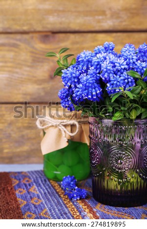 Blue bell flowers with maraschino cherry in glass jar on wooden background
