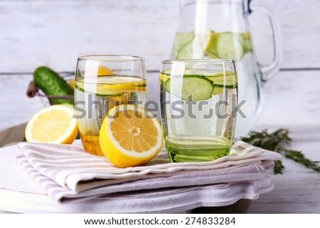 Fresh water with lemon and cucumber in glassware on wooden background