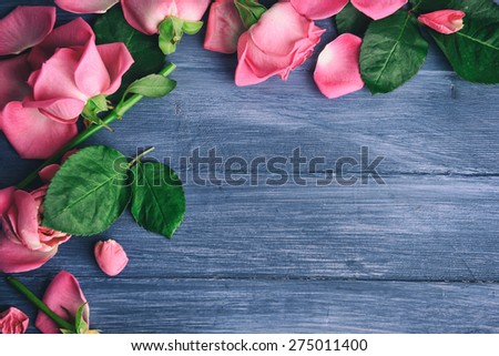 Beautiful pink petals of roses on color wooden background