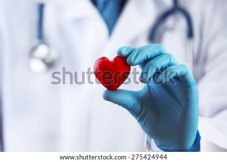 Doctor with stethoscope and small heart in hand, macro view