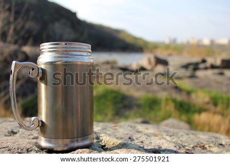 Thermos travel cup on nature background
