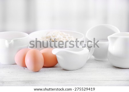 Eggs and dairy products on wooden table on curtain background