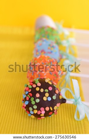 Sweet cake pops on table on yellow background