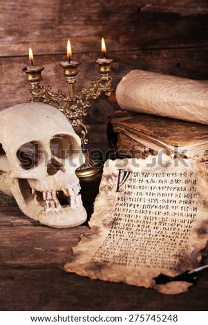 Still life with human skull, retro letter and candlelight on wooden table, closeup