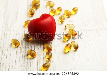 Red heart and cod liver oil, on wooden background