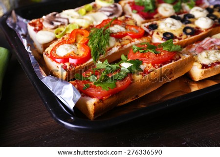 Different sandwiches with vegetables and cheese on pan on table close up