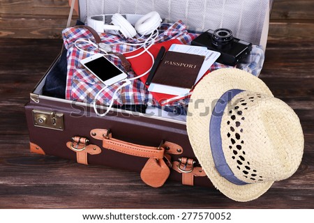 Packed suitcase of vacation items on wooden background
