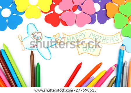 Happy Mothers Day message written on paper with pencils and decorative flowers close up