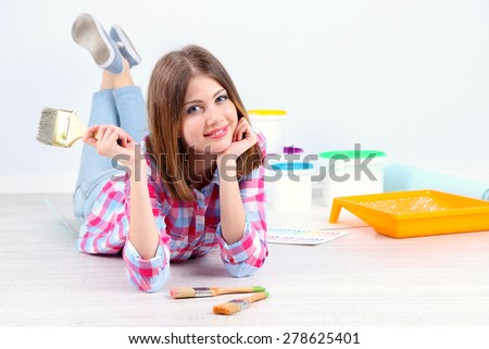 Beautiful girl lying on floor with equipment for painting wall