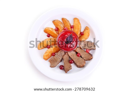 Beef with cranberry sauce, roasted potato slices on plate, isolated on white