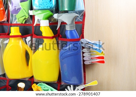 Household chemicals in holder hanging on wooden door, closeup