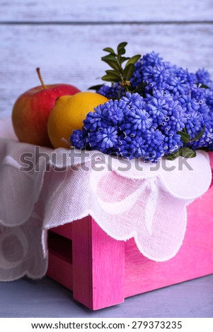 Blue bell flowers with fruits in crate on wooden background