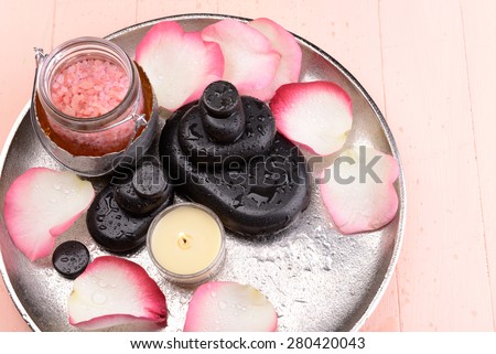 Spa stones, sea salt and rose petals on tray, on light background