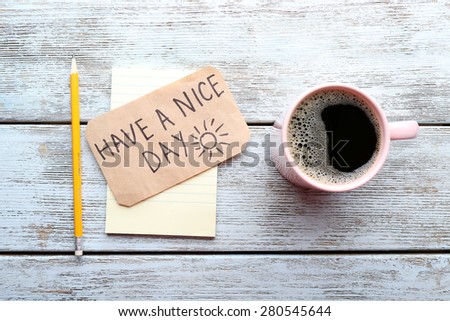 Cup of coffee and Have A Nice Day massage on wooden table, top view