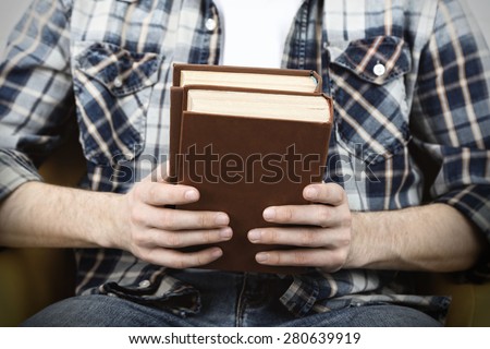 Young man reading book, close-up, on light background