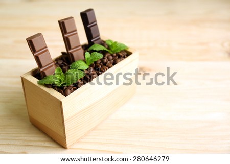 Still life with set of chocolate in wooden box of coffee grains on wooden background