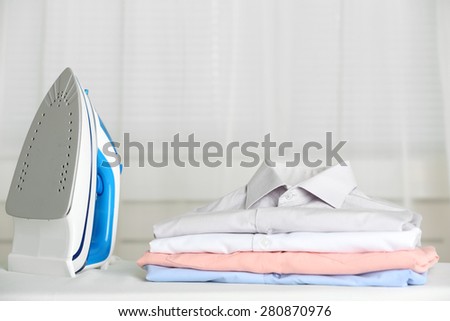 Pile of clothes and electric iron on fabric background