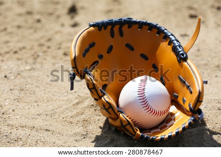 Baseball ball and glove on sand