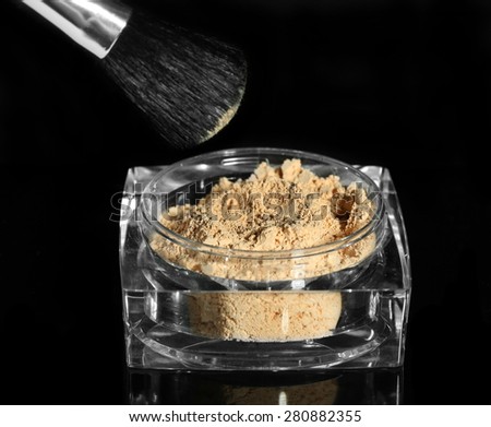 Jar with loose cosmetic powder and makeup brush, isolated on black