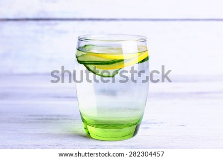 Fresh water with lemon and cucumber in glass on wooden background