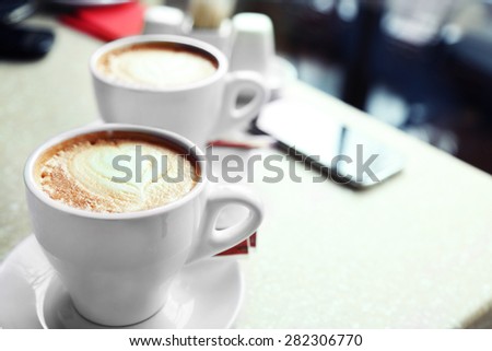 Cups of cappuccino with heart on foam on table in cafe