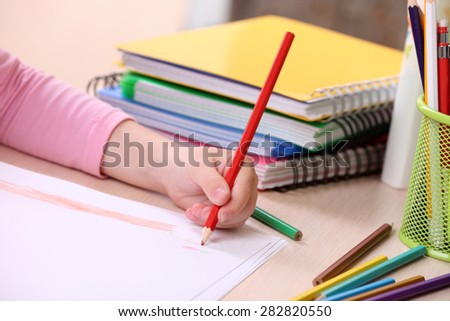 Kids hand drawing on notebook at desktop, closeup
