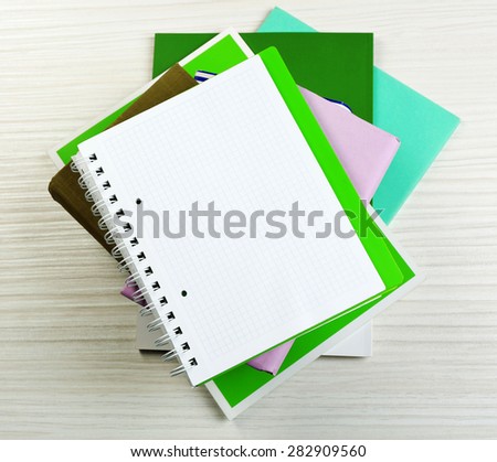 Notebook on top of pile of books and magazines on wooden background