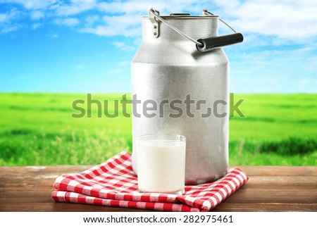 Retro can for milk and glass of milk on wooden table, on white background