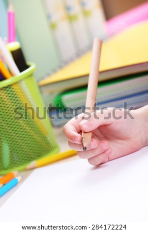 Kids hand drawing on notebook at desktop, closeup