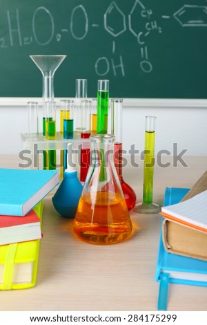 Desk in chemistry class with test tubes on green blackboard background