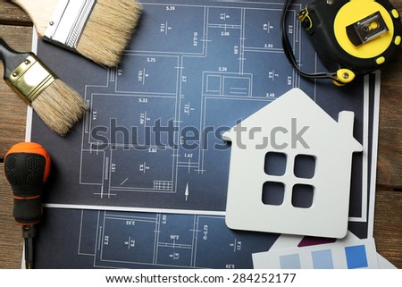 Color samples, decorative house, gloves and paintbrushes on wooden table background