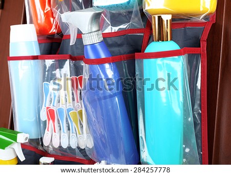 Household chemicals in holder hanging on wooden door, closeup