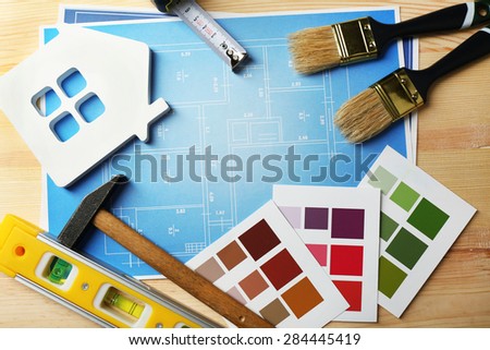 Construction instruments, plan, color samples and brushes on wooden table background