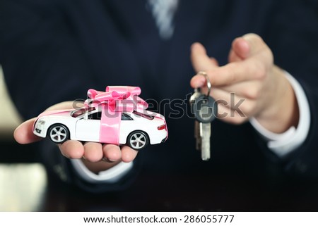 Man holding model of car and keys in his hands