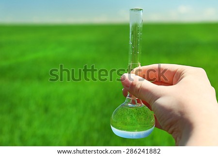 Female hand with test tube over natural background