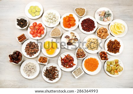 Different products on saucers on wooden table, top view