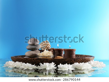 Spa still life with flowers and candlelight on blue background