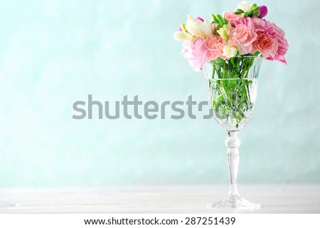 Beautiful spring flowers in glass vase on light blue background