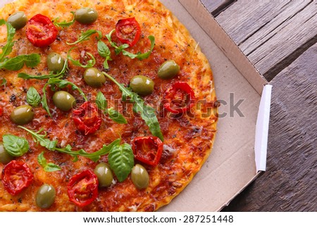 Pizza in box on wooden table, closeup