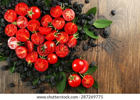 Cherry tomatoes with raisins arranged in heart shape on wooden background