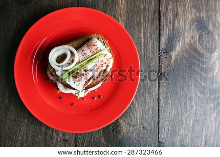Sandwiches with lard and onion on plate on wooden background