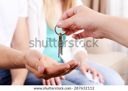 Real estate agent giving keys to young couple, closeup