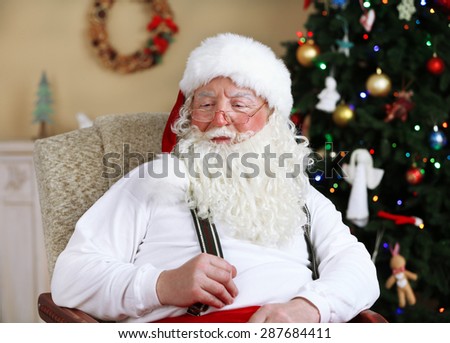 Santa Claus sitting in comfortable chair near fireplace at home