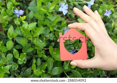 Female hand holding toy house outdoors