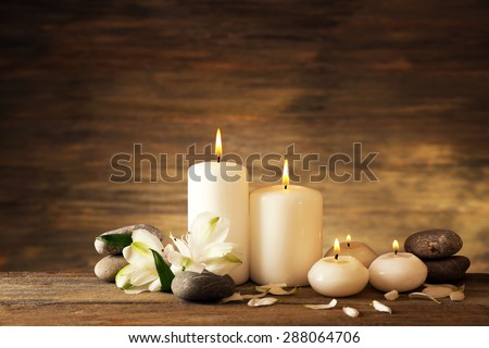 Beautiful composition with candles and spa stones on wooden background