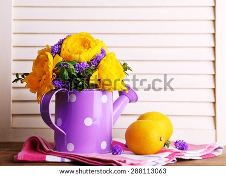 Composition with fresh spring flowers in water can on wooden background