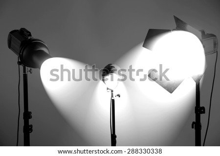 Photo studio with lighting equipment on grey wall background