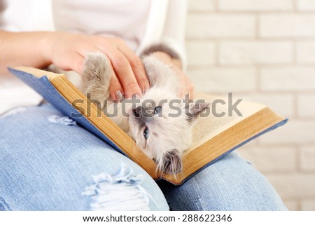Young woman holding cat and old book, close-up