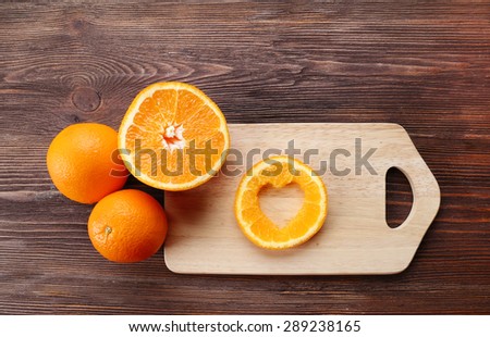 Orange slice with cut in shape of heart and fruits on wooden background