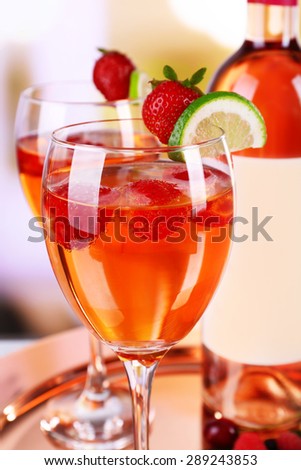 Glasses of wine with strawberries and lime on metal tray on blurred background